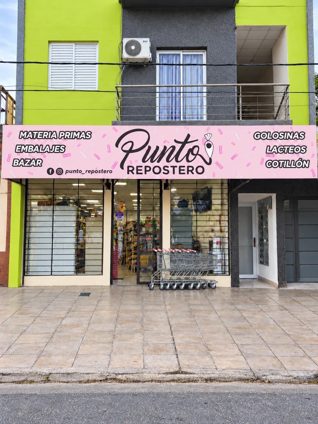 Frente del local de Punto Repostero: cartel rosa con el logo sobre las vitrinas, carros de compra en la puerta y las góndolas con mercadería adentro